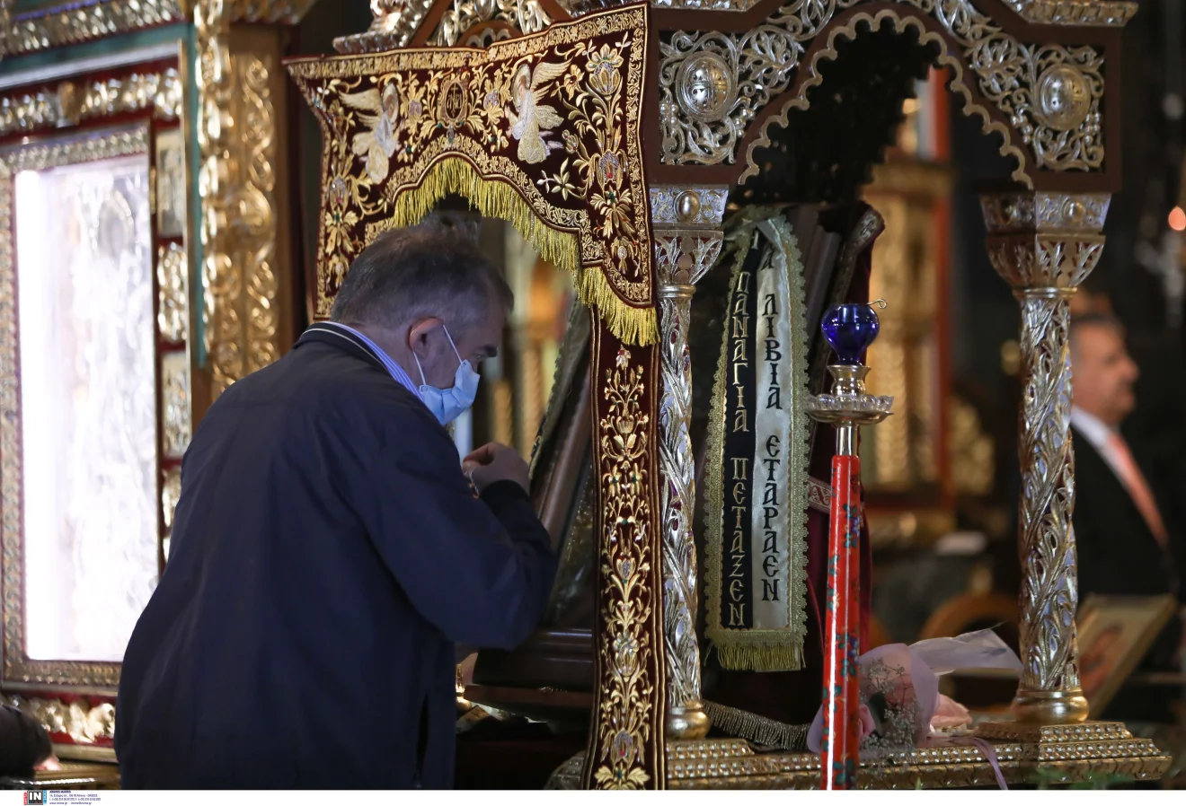 Πιστός προσκυνά στο εσωτερικό ορθόδοξου ναού, μπροστά σε περίτεχνο επιτάφιο και εκκλησιαστικά κειμήλια. Πηγή: INTIME.